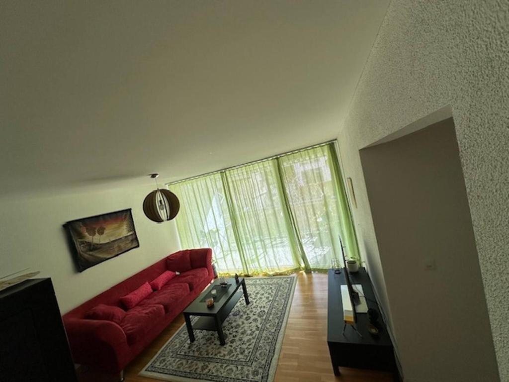 a living room with a red couch and a large window at A cozy room with double bed in semi shared Flat in Wallisellen