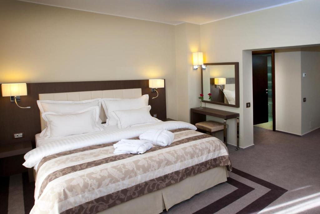 Hotel Pietroasa في بوزاو: غرفة فندق بسرير كبير عليها مناشف