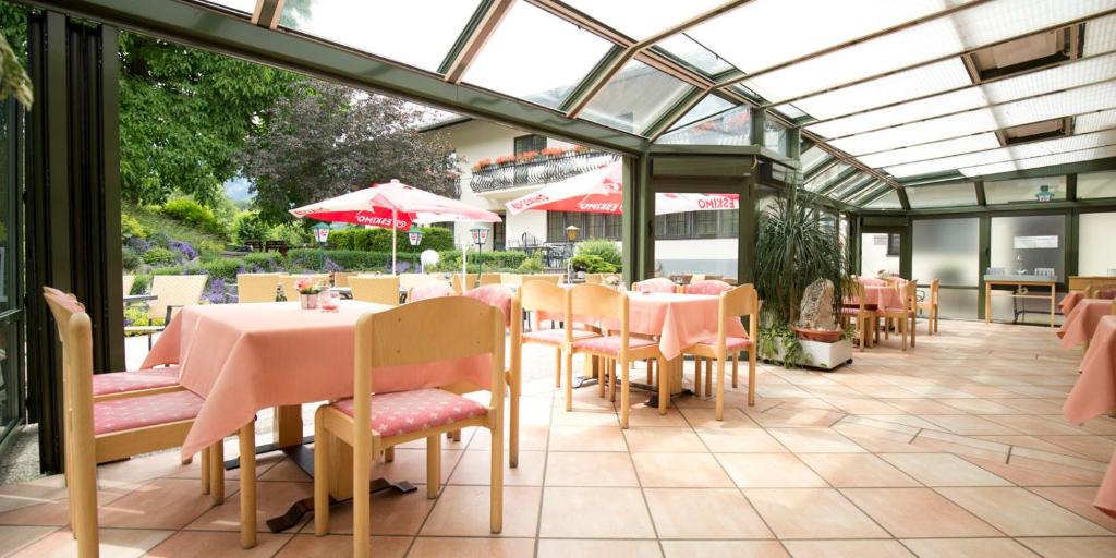 ein Restaurant mit rosa Tischen und Stühlen in einem Wintergarten in der Unterkunft Flackl - Wirt in Reichenau