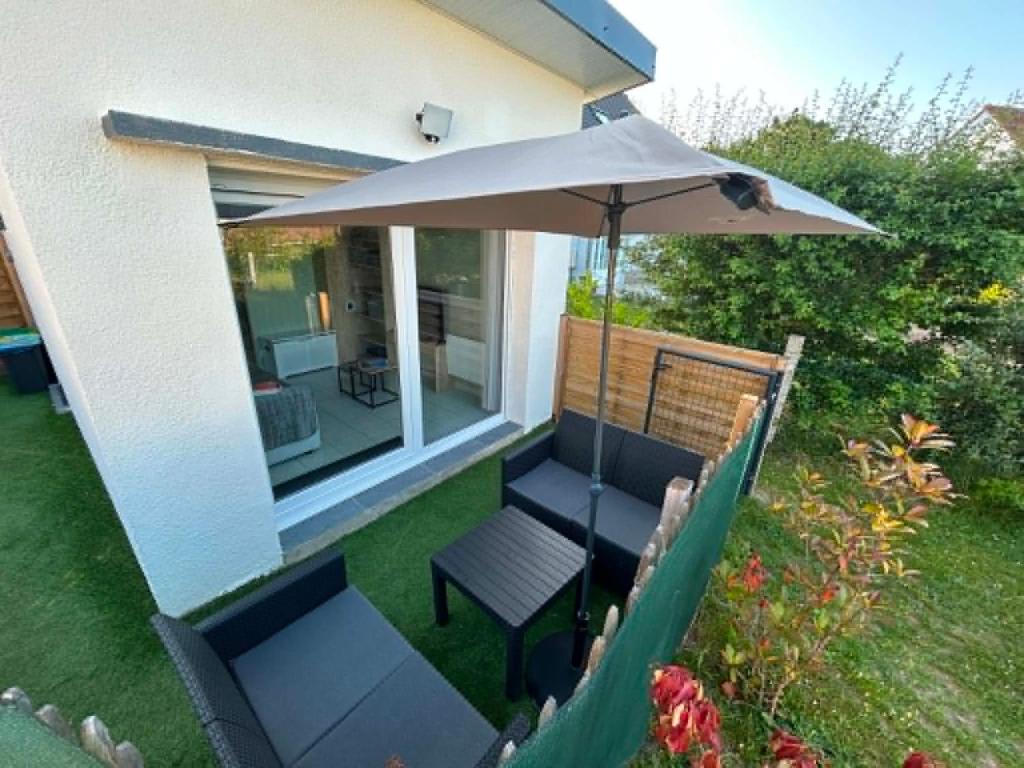 a patio with an umbrella and a chair and a table at Le Petit Studio de Merlimont in Merlimont