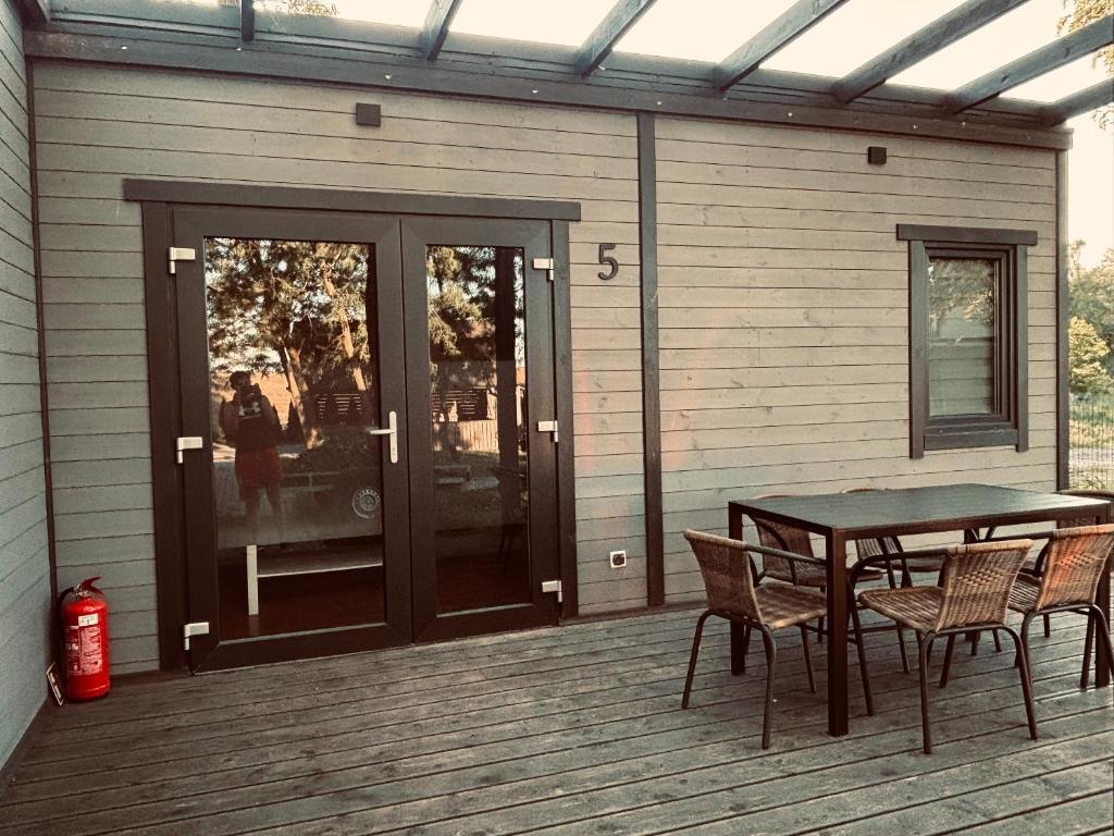 a patio with a table and chairs on a house at Domki letniskowe in Ostrów Warcki