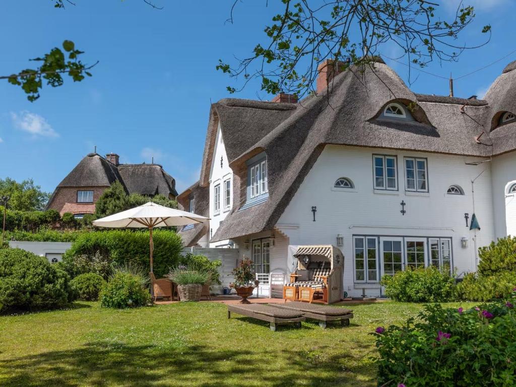 a house with a thatched roof and a yard at Ferienhaus Klenterdeel in Keitum