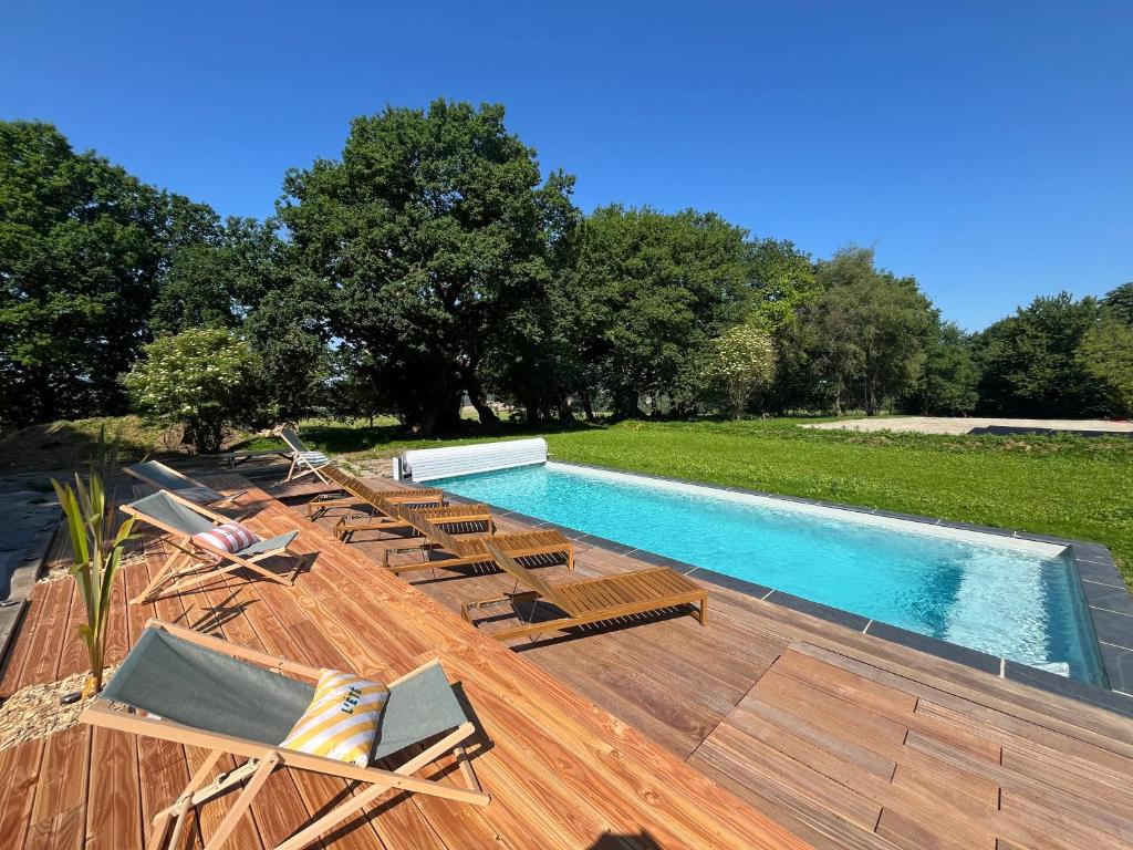 a swimming pool with chaise lounges and chairs around it at L'échappée in Neulliac