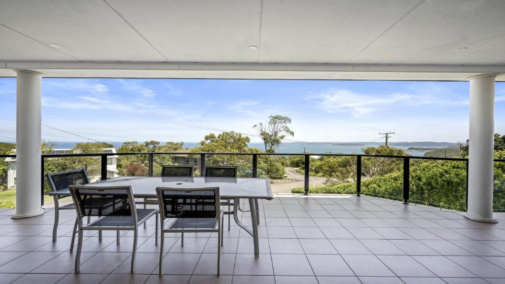 a dining room with a table and chairs on a balcony at 'Gone Coastal' by HolidayCo in Killcare