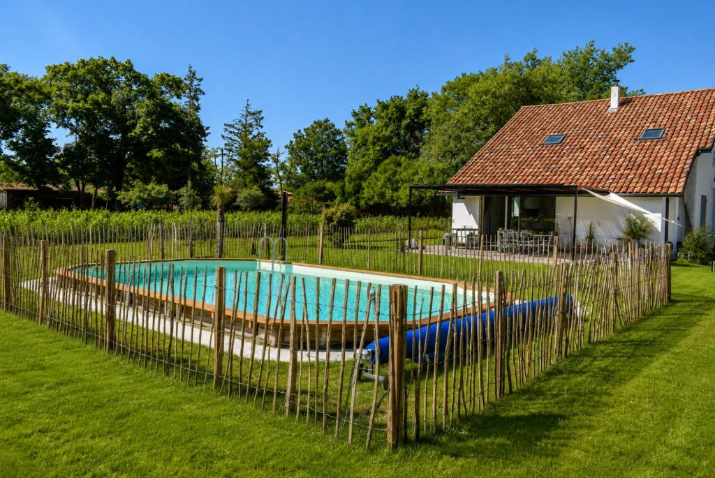 a fence around a swimming pool in a yard at Élégance et nature votre refuge entre mer et forêt in Vielle-Saint-Girons