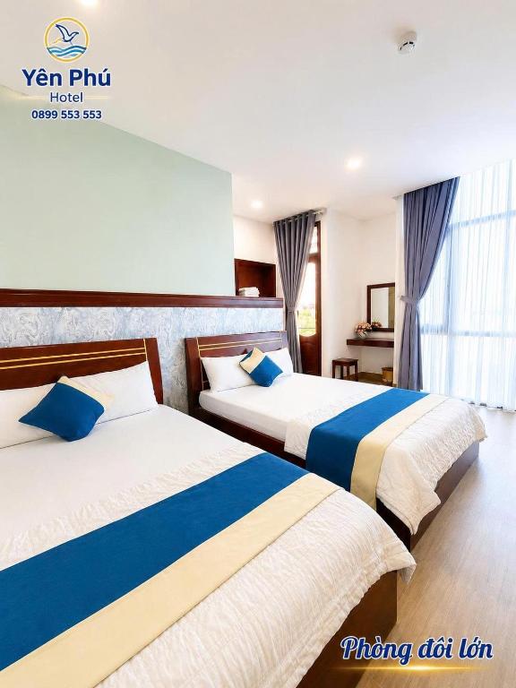 a hotel room with two beds with blue and white sheets at Yen Phu Hotel Tuy Hòa in Tuy Hoa