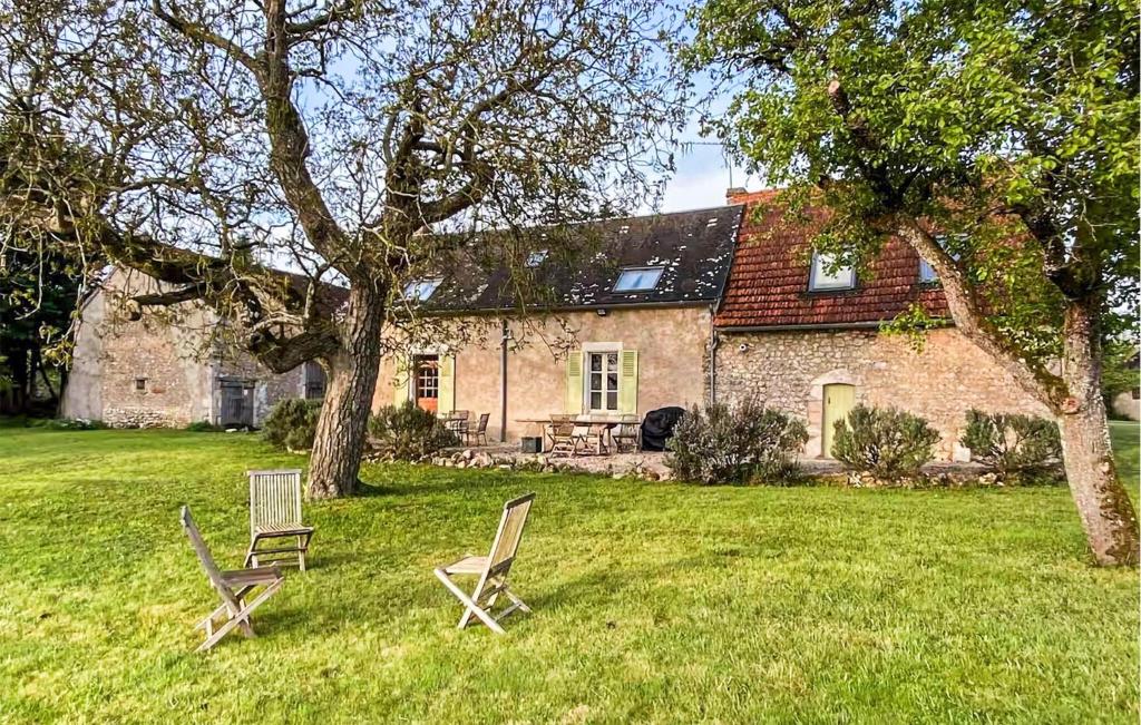 two chairs sitting in the grass in front of a house at Cottage À La Campagne in Mérigny
