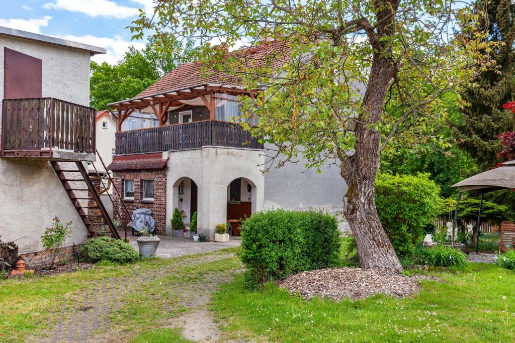 a house with a balcony and a tree at Ferienwohnung Waldglück in Lauchhammer