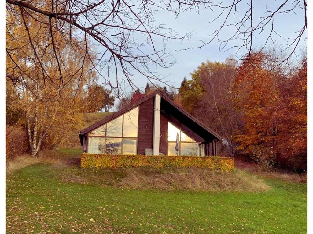 a house with glass windows on a grass field at Chalet de Cligneval in Malmedy