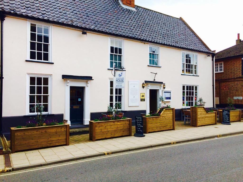 a white house with wooden planters on a sidewalk at Sutherland House in Southwold