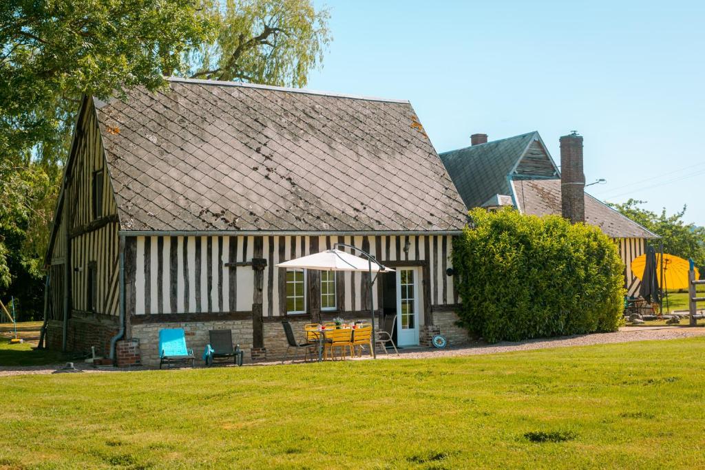 a house with an umbrella and chairs in front of it at Gîte de caractère - La Grangette in Saint-Julien-le-Faucon