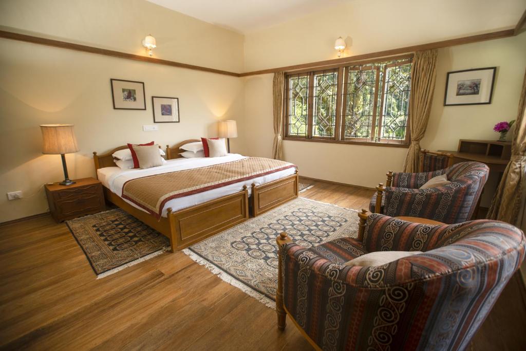 a bedroom with a bed and two chairs at Sinna Dorai's Moulmein House in Vālpārai