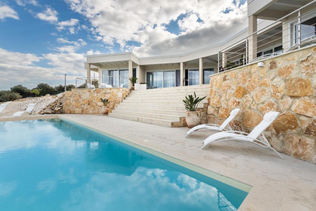 a house with a swimming pool and two white chairs at Elaia Bioglam Relais in Casa Modica
