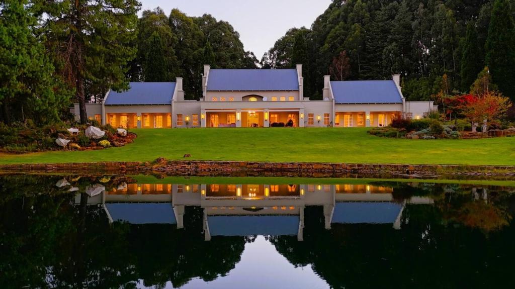 a house with a pond in front of it at Private Manor Estate Fly Fishing Sleeps 18 in Dullstroom
