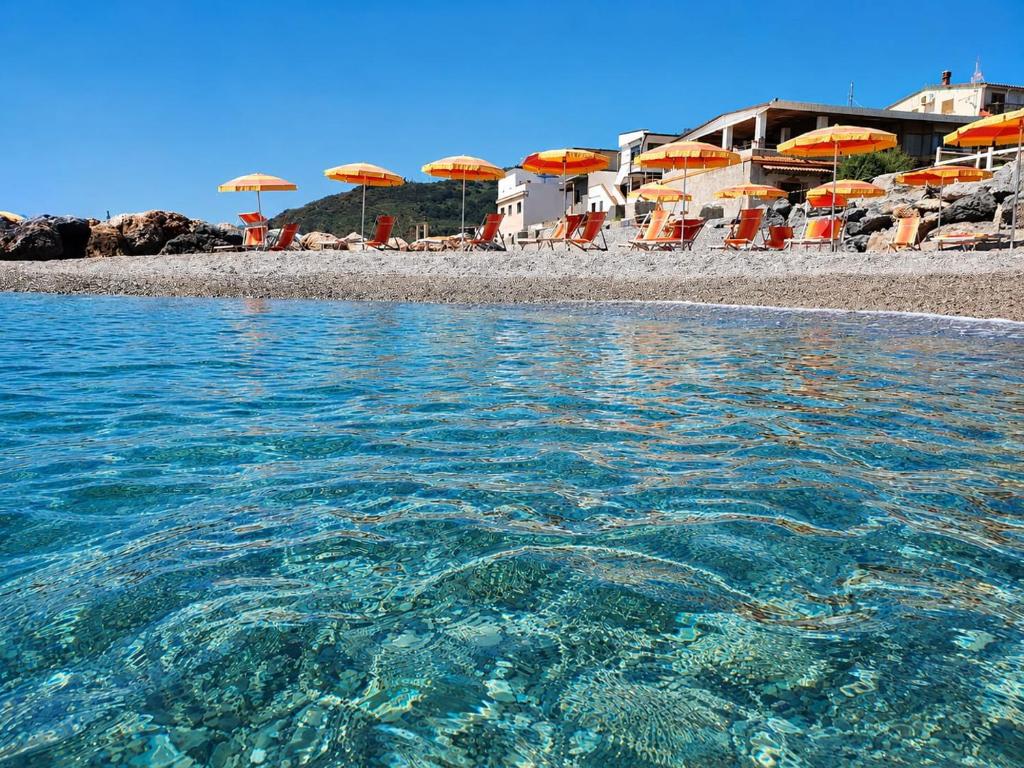 a beach with chairs and umbrellas and the water at Sole E Mare in Marina di Fuscaldo