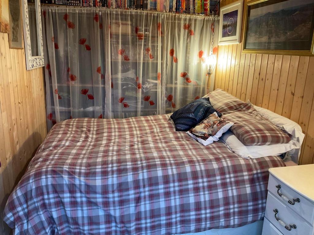 a small bedroom with a bed with a plaid blanket at Sleeps 2 includes breakfast in Garve