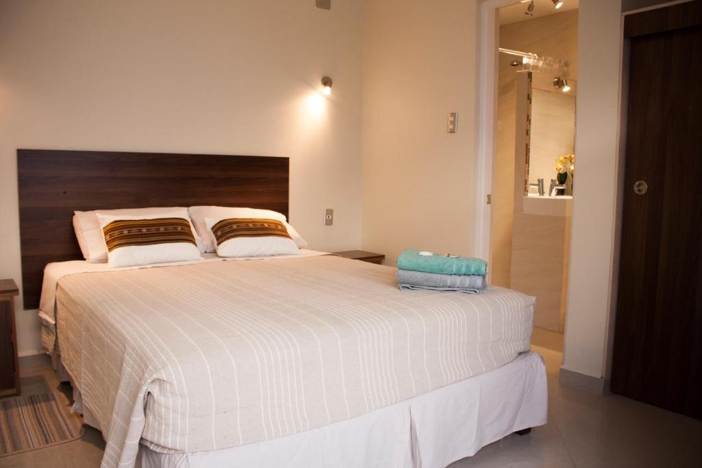 a bedroom with a large white bed with a wooden headboard at Hostal Anpaymi Atacama in San Pedro de Atacama