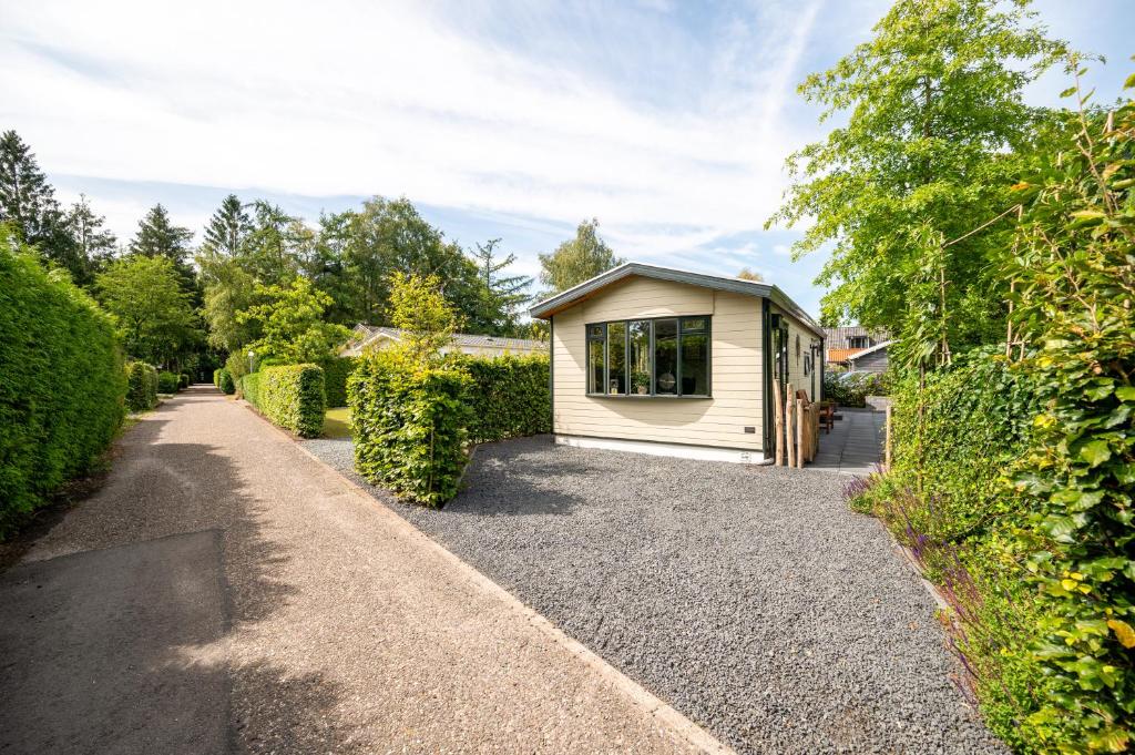 a small house on a gravel driveway at Chalet De Eik, sfeervol chalet met tuin, op de Veluwe in Putten