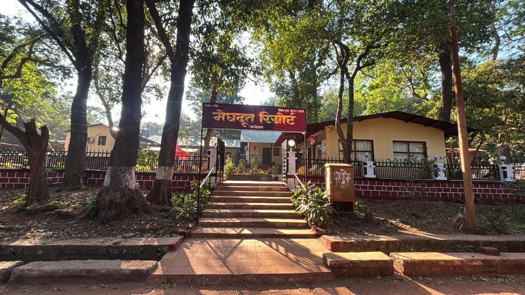 a sign in front of a building with trees at Meghdoot New Resort in Matheran