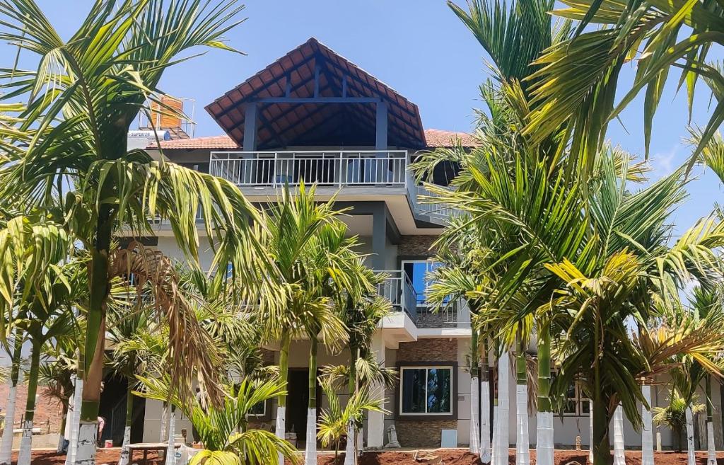 a house with palm trees in front of it at New Peak By The Lake in Chikmagalūr