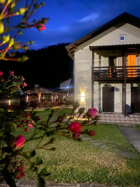 a house at night with flowers in front of it at Pensiunea Ana in Ceahlău