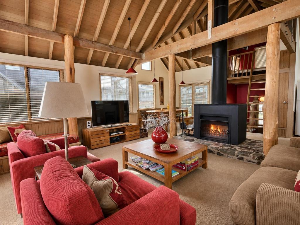 a living room with red furniture and a fireplace at 360 Degrees, alpine-getaways in Dinner Plain