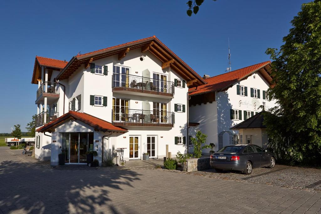 un gran edificio blanco con un coche aparcado delante de él en Landhotel Grüner Baum en Westendorf