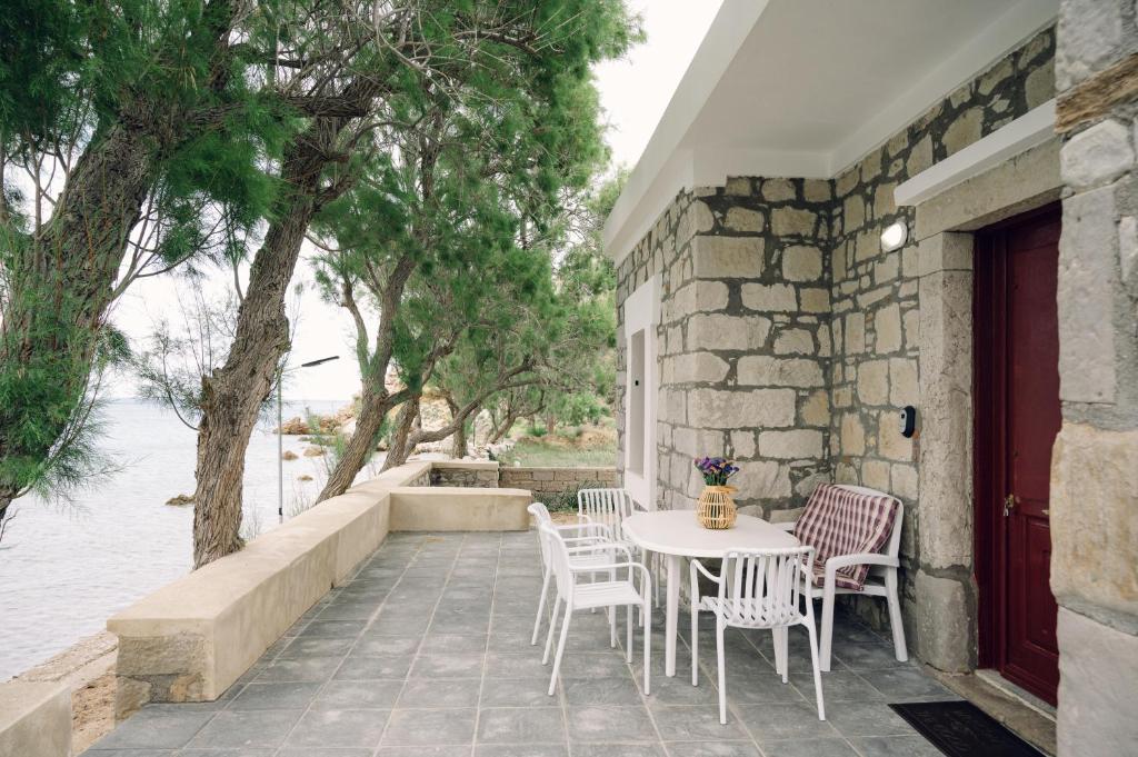 a table and chairs on a patio near the water at Emporios 1930, Seafront stone house in Emporeiós