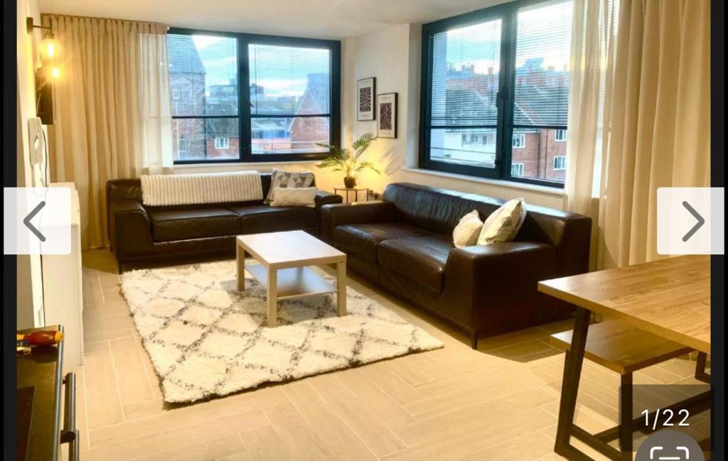 a living room with a black leather couch and a table at Spacious 3BR City Centre Apartment Free Parking in Liverpool