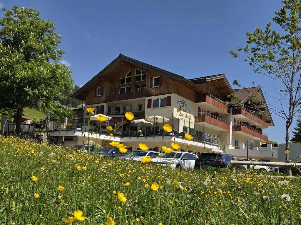 a building with cars parked in a field of flowers at Hotel Steinbock in Mittelberg