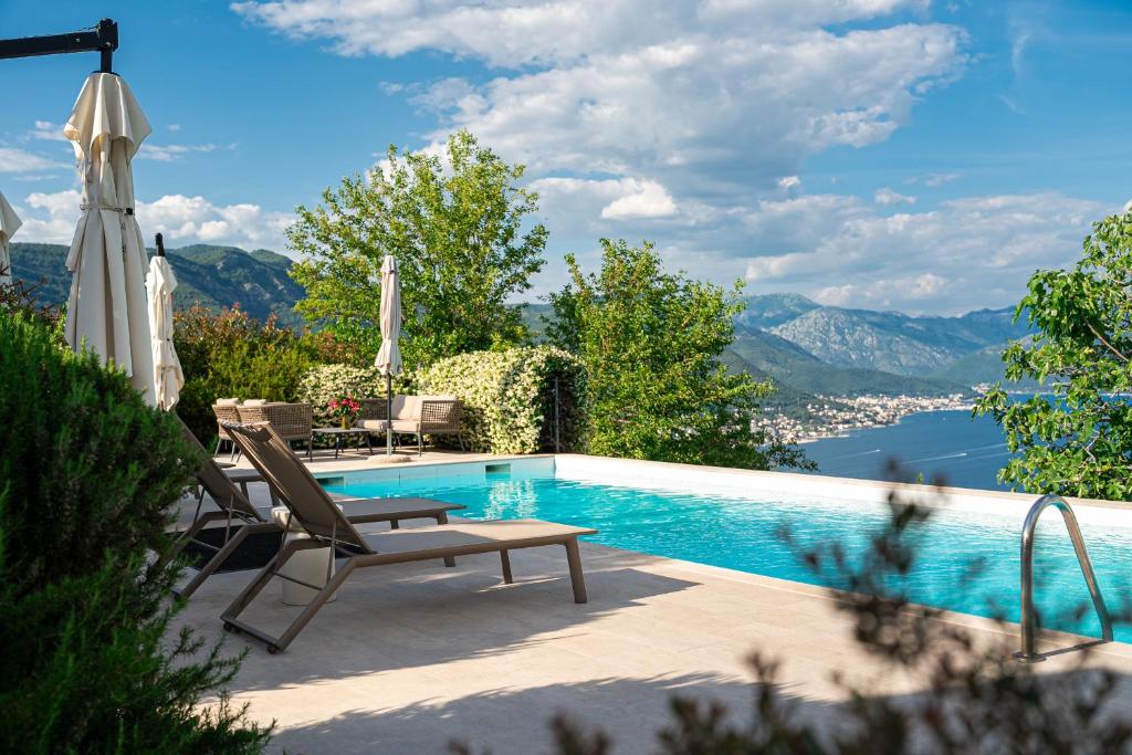 a pool with chairs and an umbrella and a view of the water at Villa Stari Mlin in Luštica