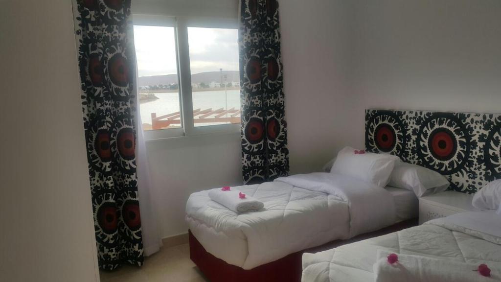 a room with two beds and a window and a couch at Twin Lagoon Apartment at White Villas El Gouna in Hurghada