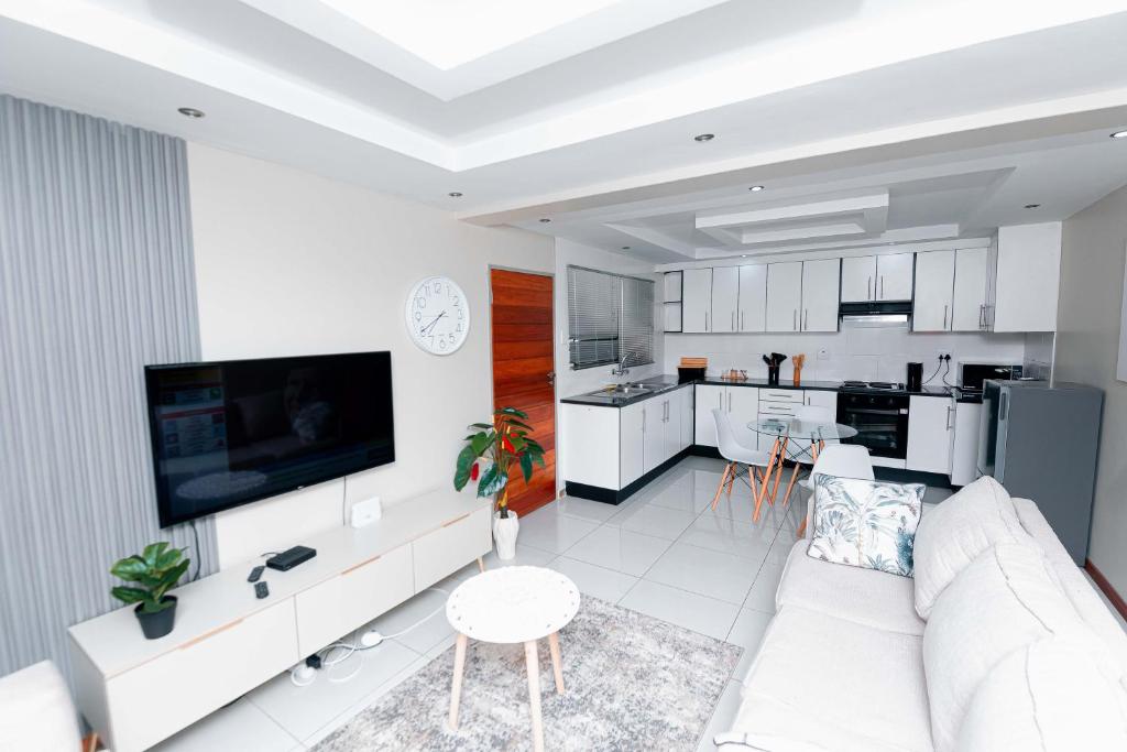 a white living room with a white couch and a kitchen at Goshen villas in Mbabane