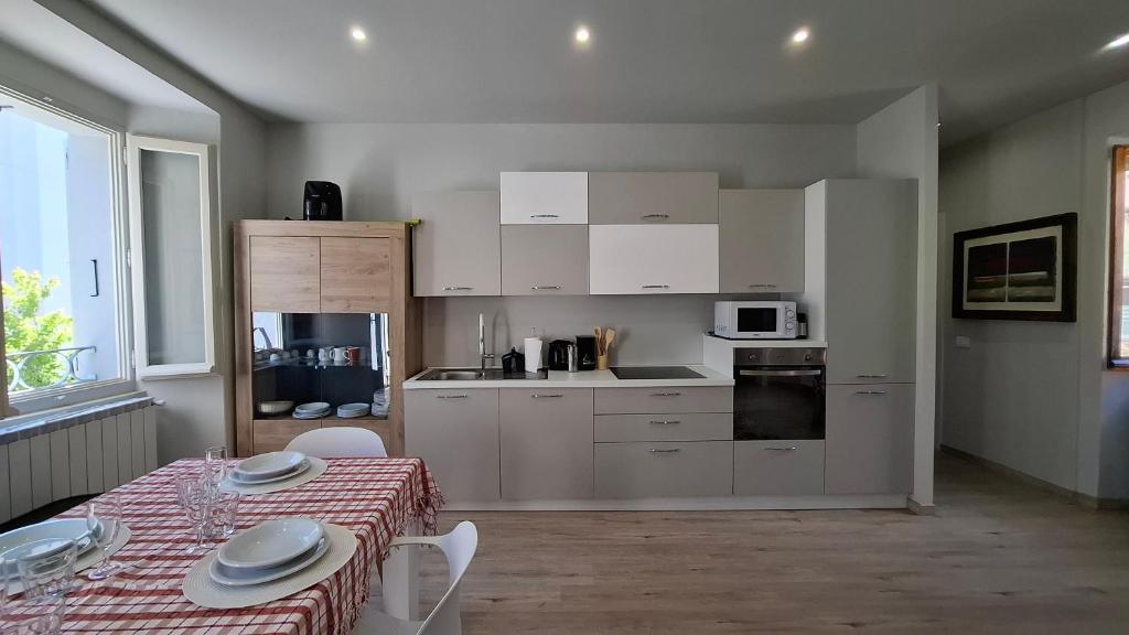 a kitchen with white cabinets and a table with a table cloth at Risorgimento 8 appartamento centro Santa Maria Maggiore Valle Vigezzo in Santa Maria Maggiore