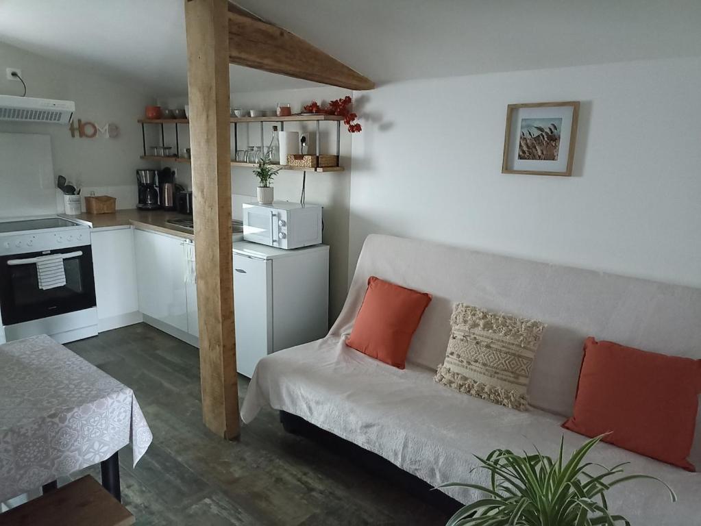 a living room with a couch and a kitchen at L'Eden maison avec jardin proche du Puy dufou in Les Landes-Génusson