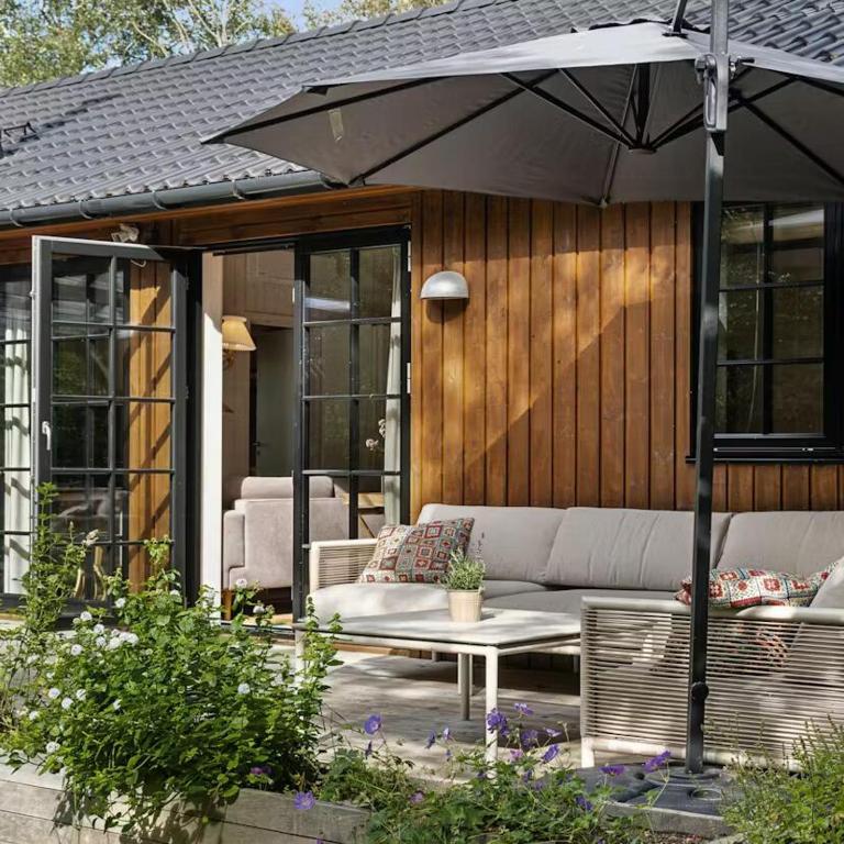 a patio with a couch and a table and an umbrella at Nordic Nature Hideaway in Yderby