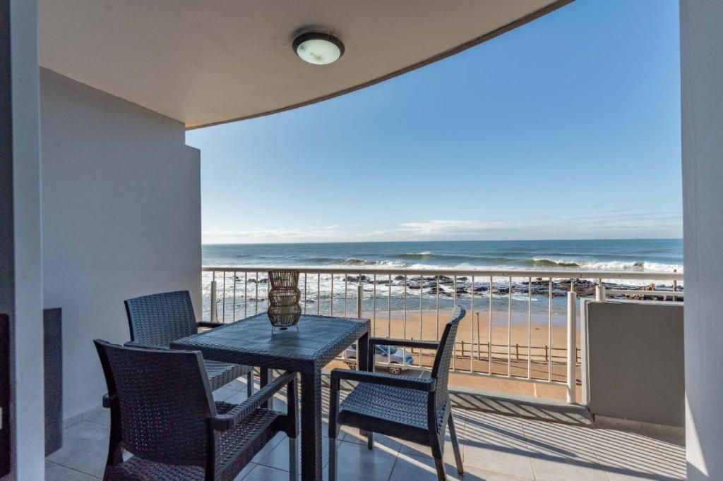 a balcony with a table and chairs and a view of the beach at Cozumel 216 in Umdloti