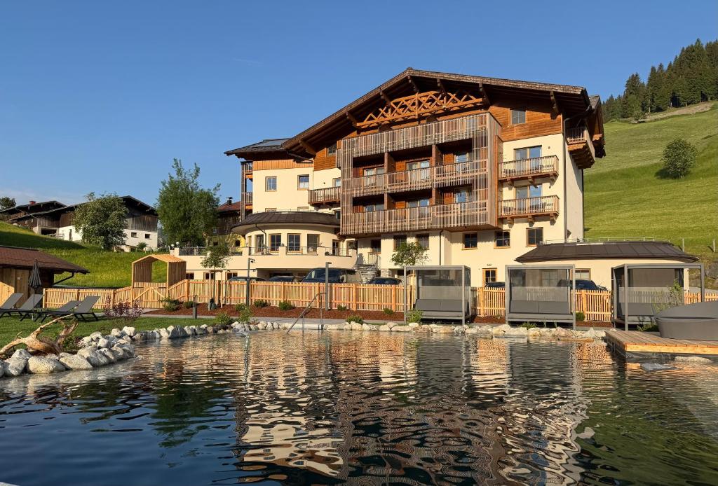 a large building next to a large body of water at Berghotel Alpenklang in Grossarl