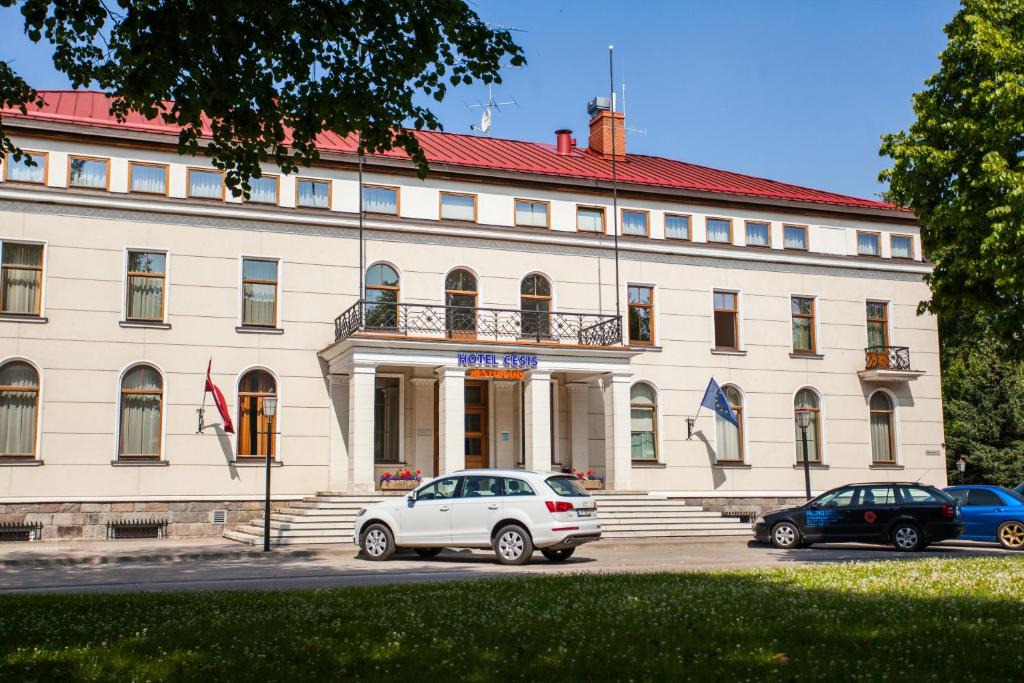 a white car parked in front of a building at Hotel Cēsis in Cēsis