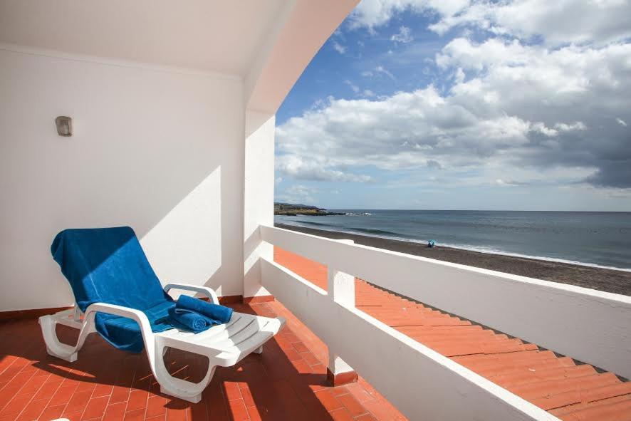 a blue chair sitting on a balcony overlooking the ocean at Aparthotel Barracuda in Ponta Delgada