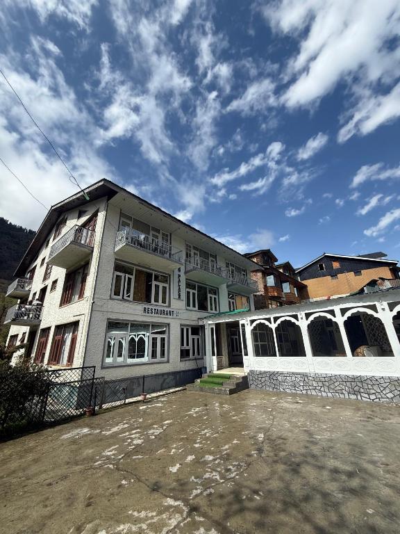 a large white building with a lot of windows at Hotel king palace in Pahalgām