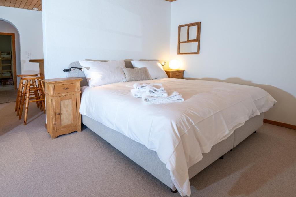 a bedroom with a bed with white sheets and a table at Garden apartment with mountain views & barbecue in Lenz