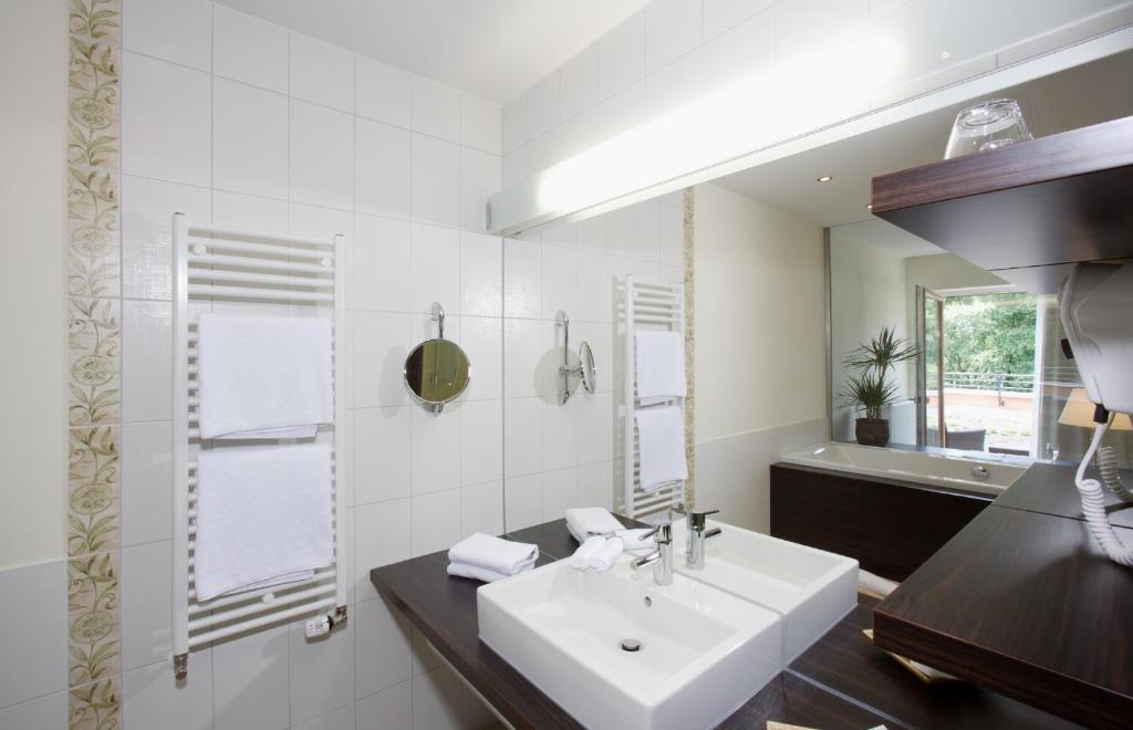 a white bathroom with a sink and a mirror at Heide Spa Hotel &amp; Resort in Bad Düben