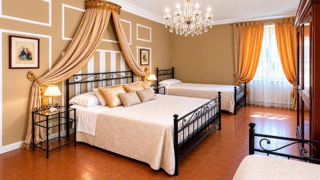 a bedroom with two beds and a chandelier at Foresteria di Palazzo Picedi - Historic Rooms Sarzana in Sarzana