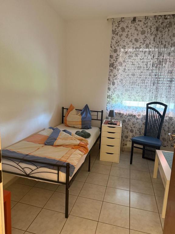 a bedroom with a bed and a chair and a window at Sonnenblick Kleiberweg in Mosbach