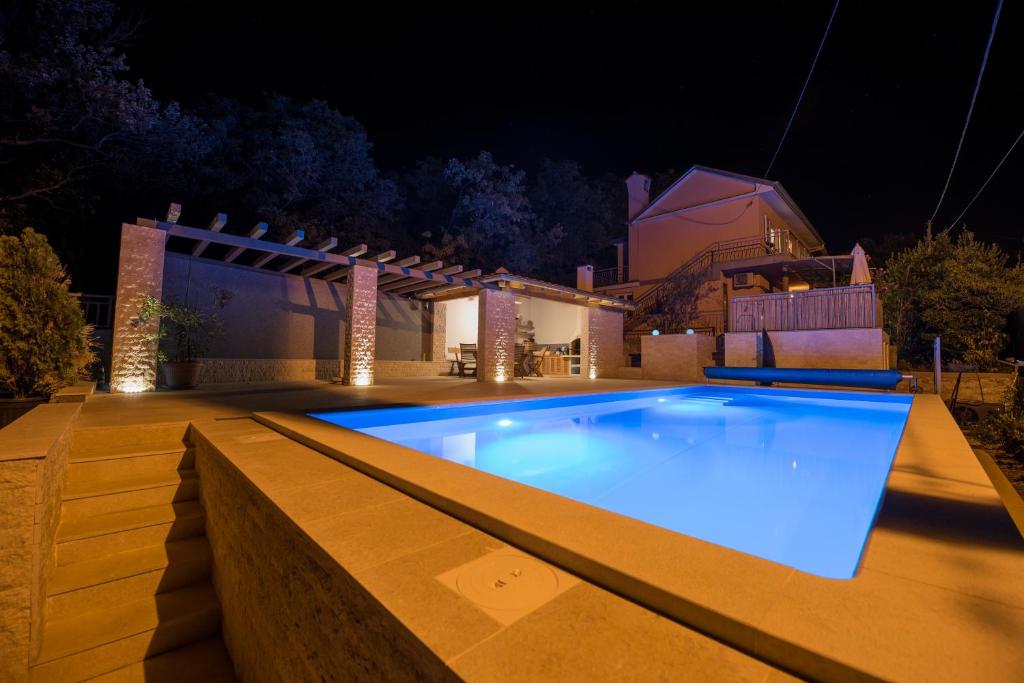 a swimming pool at night with a house in the background at Villa Sunset in Jadranovo