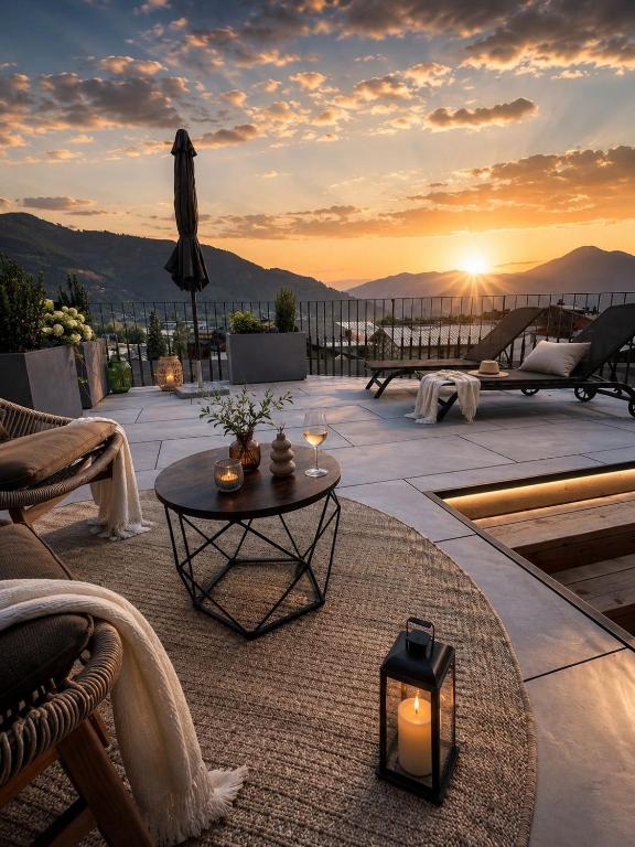 a patio with a table with a sunset in the background at Margarethenstein Boutique Hotel including Zell am See Kaprun summercard and Air condition in Kaprun