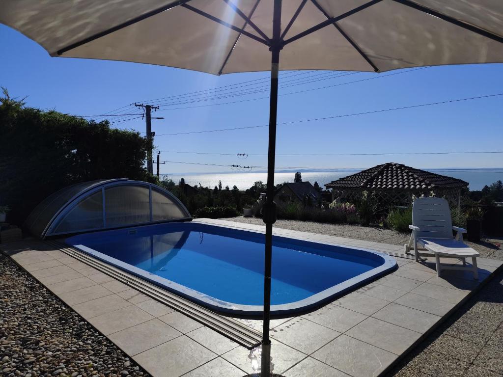 a blue swimming pool with an umbrella and a chair at Herczeg Villa in Balatongyörök
