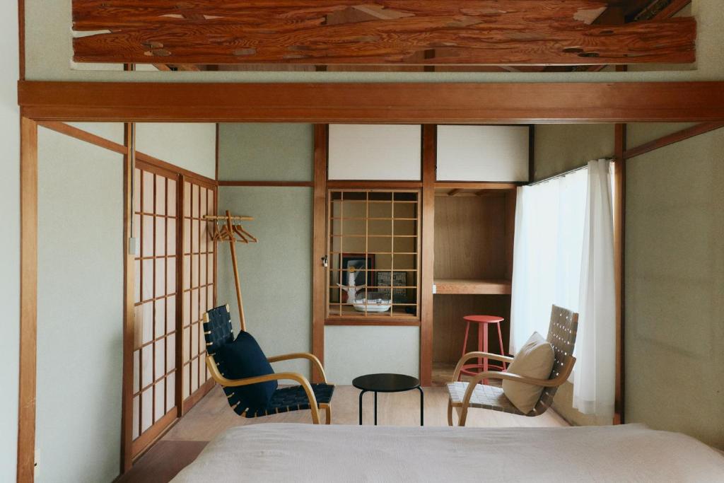 a bedroom with a bed and chairs in a room at kawasakike in Takamatsu