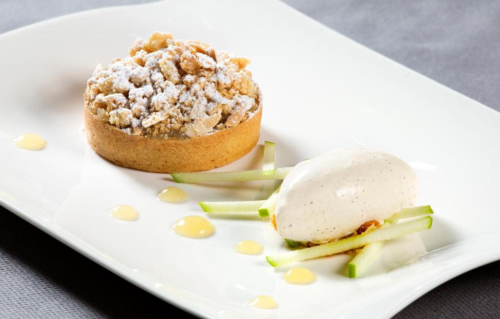 a dessert on a white plate with a scoop of ice cream at Hostellerie Stafelter in Walferdange